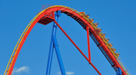 red and yellow roller coaster peak with blue sky