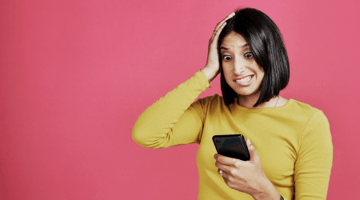 Woman in yellow sweater looking at phone and remembering something she forgot to do