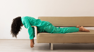 Woman in green pajamas feeling stuck and laying on couch