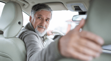 senior man putting car in reverse to backup