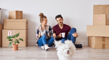 couple with small white dog and moving boxes