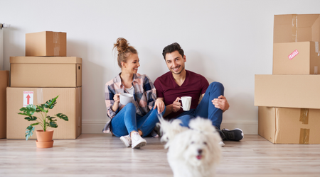 Couple with small white dog and moving boxes