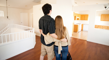 couple with backs to us standing in empty house