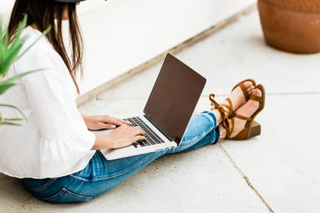 woman sitting on ground working on laptop