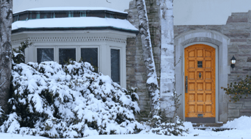 snowy landscape of home exterior with oak door