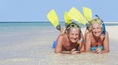 retired couple with snorkel gear on the beach