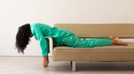 Woman in green pajamas feeling stuck and laying on couch