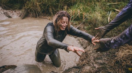 Woman on a mud run getting a helping hand from others