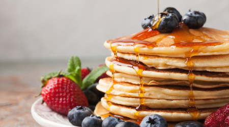 stack of pancakes piled high with syrup and berries