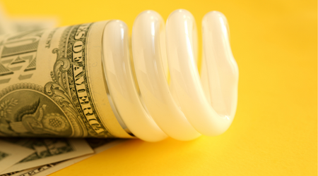LED bulb with cash wrapped around on yellow background