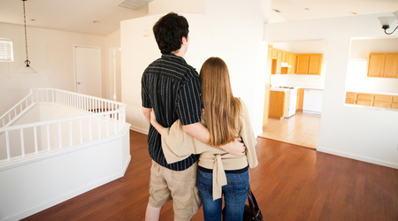 couple standing facing away in empty house